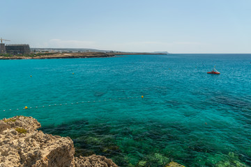 CYPRUS, NISSI BEACH - MAY 12/2018: Tourists swim on catamarans and kayaks in the popular bay of the Mediterranean Sea.
