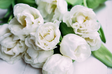 Bouquet of white tulips on a wooden background with space for text. 
