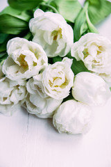 Bouquet of white tulips on a wooden background with space for text. 