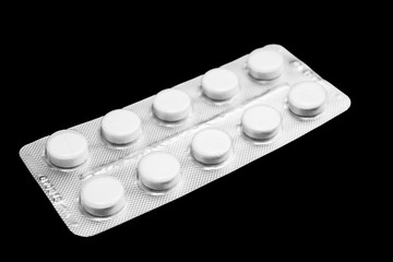 white pack with pills on black background, close-up
