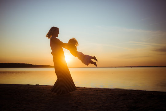Banner with silhouette of mom and baby on a sunset background. Beautiful landscape suitable for wallpaper. The theme of love and motherhood.
