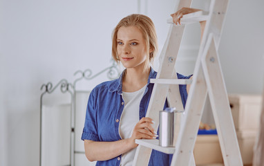 Beautiful young woman on a white wooden stepladder. Ready to repair the room. Women housework concept