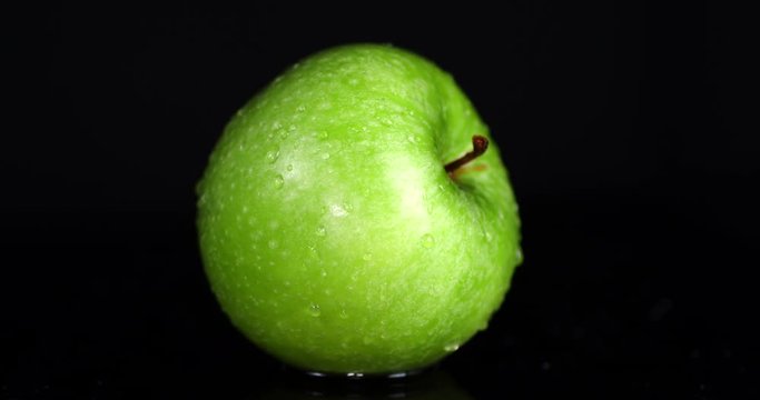 Rotating fresh green apples with water drops.