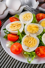 salad with boiled chicken eggs and cherry tomatoes on a wooden rustic background