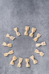 Fototapeta na wymiar Homemade pasta in the form of bows on a gray stone surface. Top view.