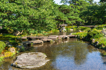 Fototapeta na wymiar Scenic pond crossed by a small stone bridge at Kenroku-en garden, Kanazawa, Japan