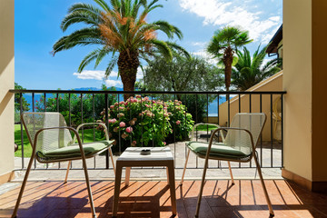 Terrace with table and chairs with view on tropical palms at Garda Lake in Gargnano in Italy