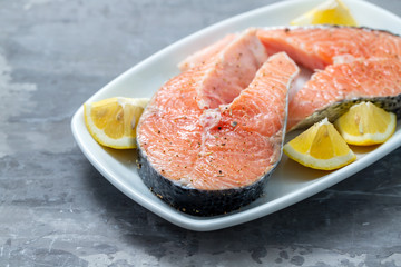 Naklejka na ściany i meble raw salmon with lemon on white dish on ceramic background