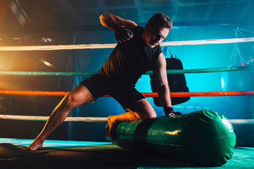 muscular man practicing mma in the boxing ring - ground and pound