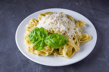 Delicious tagliatelle pasta with pesnto sauce on dark stone background