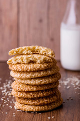 Round sesame cookies with milk and juice on the table.