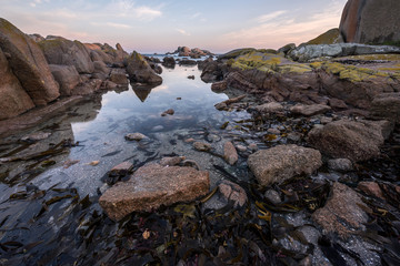 A beautiful early morning seascape, with a golden cloudy sky and rocks and reflections in the foreground, taken at Paternoster, South Africa.