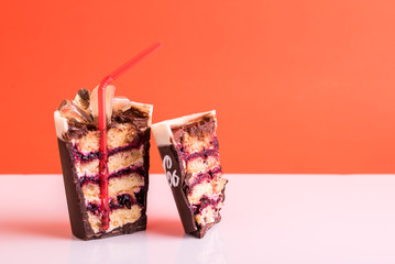 Dessert cake in the form of a glass of drink with ice and a tube on a red background.
