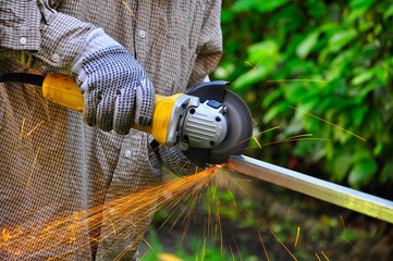 An unknown man using an angle grinder to cut metal