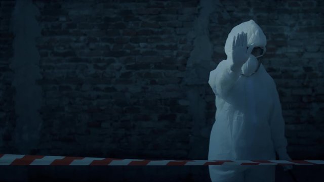 Woman with bacteriological protection suit makes a stop hand gesture.
Infectious disease area concept