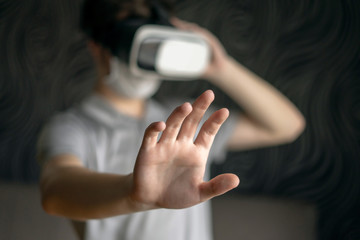 Man in a medical mask and virtual reality glasses shows a 