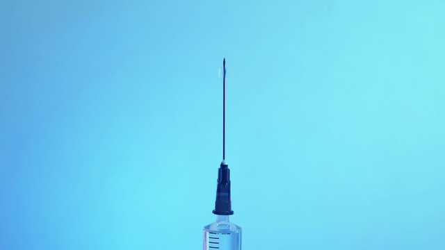 Flu vaccine. Medical care. Syringe injecting drug drops air on blue background.