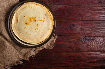 Traditional Russian homemade pancakes on a large round plate in a rustic style.