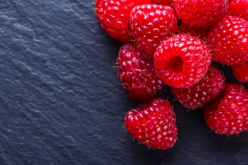 juicy fresh natural raspberries on a dark stone background
