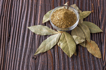 ground dried bay leaf on dark wooden rustic background