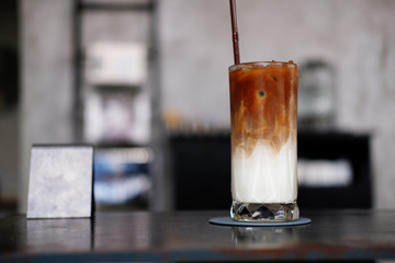 glass of coffee with ice on wooden table