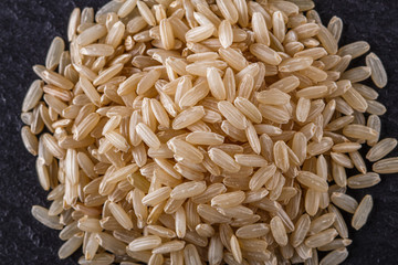raw brown rice on a dark stone background