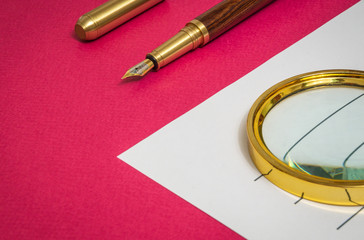Office still life on red table with gilded pen a and magnifying glass is preparing for the notes