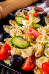 Delicious pasta salad with tomato cucumber and olives on wooden rustic background