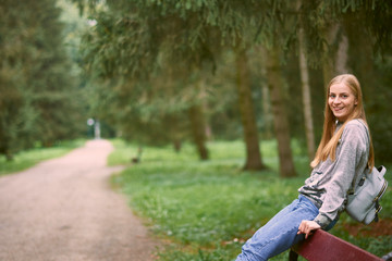Naklejka na ściany i meble Beautiful young woman is walking in the park. Young woman enjoying nature