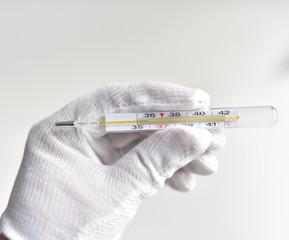 hand in a white glove with a mercury thermometer