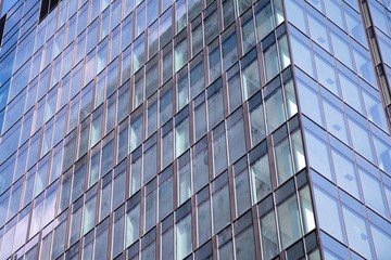 Modern curtain wall made of glass and steel. Blue sky and clouds reflected in windows of modern office building. 