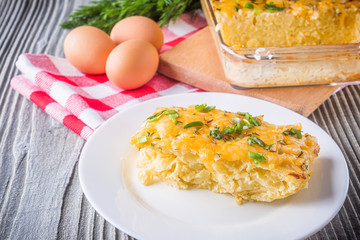 Delicious potato casserole with egg and cheese on a gray wooden background