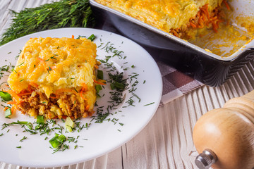 Delicious potato casserole with meat and cheese on a white wooden background