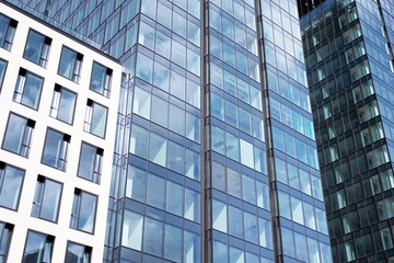 Fototapeta premium Modern curtain wall made of glass and steel. Blue sky and clouds reflected in windows of modern office building. 