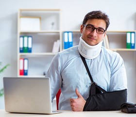 Businessman with broken arm working in office
