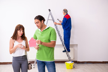 Young couple and old contractor in home renovation concept