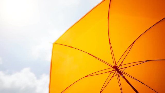 Colourful yellow umbrella spinning slowly on a sunny day. Looping animation 4KHD