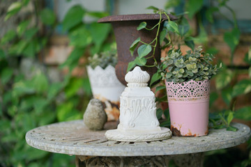 Garden decoration. Small corner in the backyard garden with flower pots, robin bird statuette and soft focus on the vintage plaster cement decor.