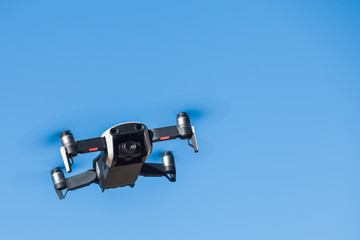 Four-propeller drone flying in nature against the blue sky. The maneuver.