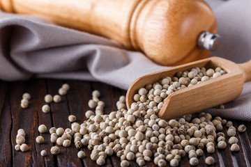 white peppercorns in wooden scoop on rustic background