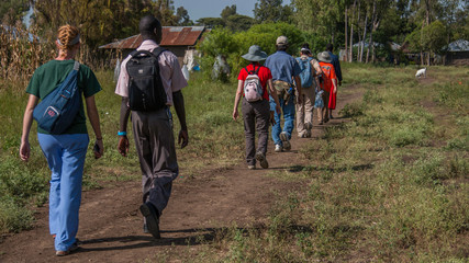 Due to the lack of roads, a Baptist Missions team hikes to the next location to begin construction of a new home for a local widow and her children in a village near Ahero, Kenya - obrazy, fototapety, plakaty