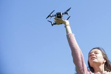 A young woman in park launches, holds the drone with her outstretched arm above her head, in another control panel.