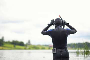 A scuba diver in a wet suit prepares