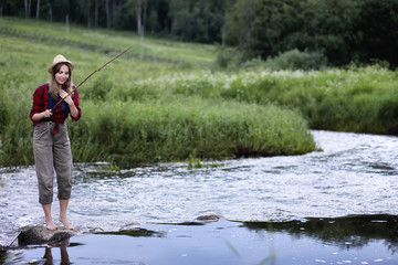 Girl by the river with a fishing rod