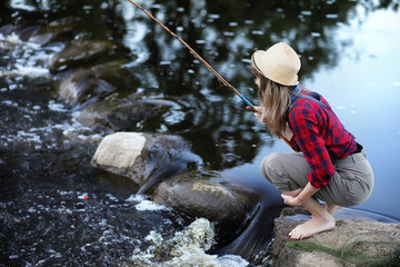 Girl by the river with a fishing rod