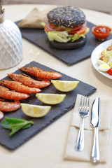 Appetizing shrimp with lemon on a black slate plate. Restaurant server of the table in the style of Provence