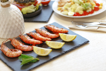 Appetizing shrimp with lemon on a black slate plate. Restaurant server of the table in the style of Provence