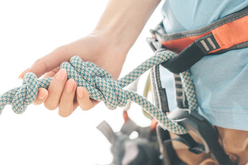 Climber in safety harness holding rope knot eight, close-up.