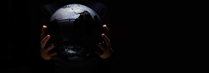 Hands of little girl hold globe sphere map isolated on black background.  COVID-19 pandemic...