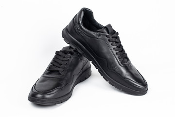 Black leather sports shoes for men on a light background. In such shoes, it is convenient for men to walk and go to work in the spring or fall